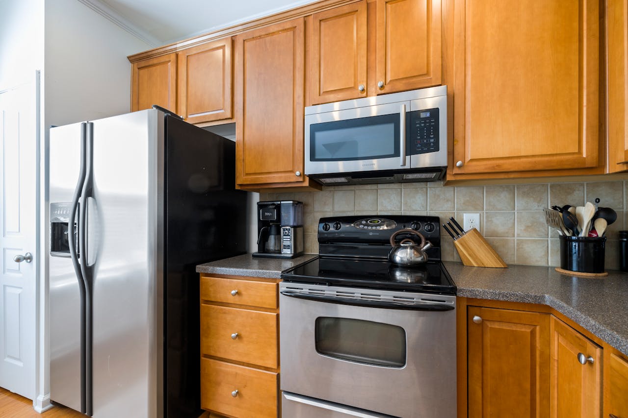 Contemporary kitchen featuring stainless steel appliances, wooden cabinets, and tile backsplash.